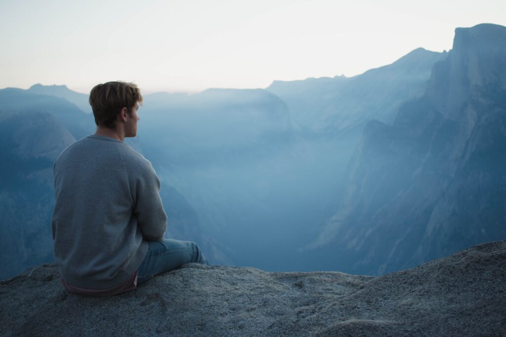 man sitting at the edge of a cliff